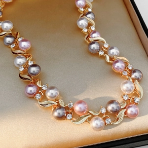 Gros plan d'un collier vintage avec perles multicolores et feuilles d'or dans son coffret