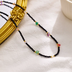 Macro detail of bohemian beaded necklace with black beads and colorful natural stones