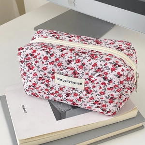 Detailed macro of floral quilted fabric pouch with zipper and brand label on art books