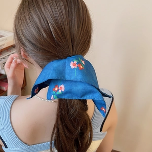 Close-up of blue floral silk scarf ponytail holder tied in a soft bow hairstyle