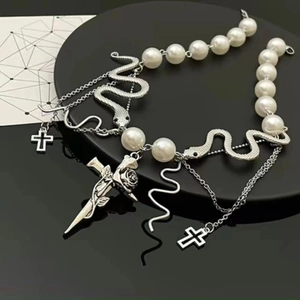 Beaded snake tassel cross necklace with rose sword pendant on a black pedestal