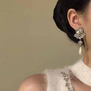 Detail of silver drop earrings with floral rhinestones and teardrop pearls on model