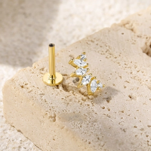 Macro shot of gold S925 sterling silver butterfly piercing stud on beige stone