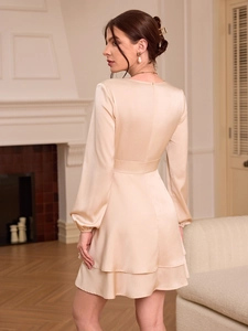 Detail view of champagne satin mini dress showing layered hem and cinched waist design