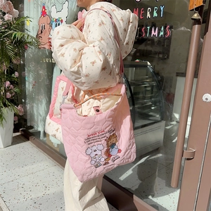 Detail of pink quilted crossbody bag with cute embroidery and beige tote bag ensemble