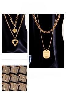 Detail showing asymmetric gold layered necklaces with heart and pearl pendants on dark velvet