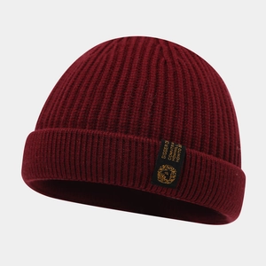 Détail montrant la texture côtelée et l'étiquette tissée sur un bonnet d'hiver bordeaux