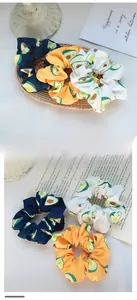 Three-piece set of avocado print hair scrunchies in navy, orange, and cream colors