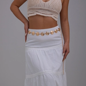 Detail view of golden shell textured alloy waist chain worn over a white summer dress