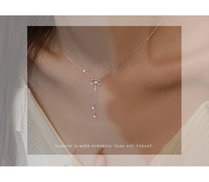 Detail of silver bow tassel necklace with sparkling diamonds worn on a neck