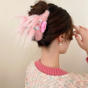 Close-up of pink fuzzy monster hair claw clip with funny eyes on a model's hair bun