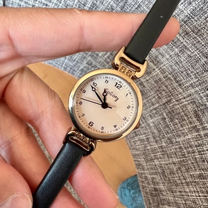 GoGoey women's watch with a small round gold case, black leather strap, and cream-white dial