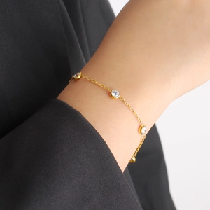 Detailed view of elegant gold chain bracelet with round bezel-set cubic zirconia on wrist