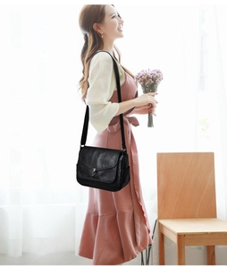 Detail view of a black soft leather shoulder bag with a silver metal twist lock clasp