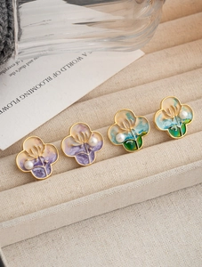Macro detail of oil painting style clover earrings with purple enamel and pearl inlay