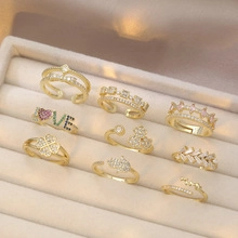 Close-up of gold plated rings set with clover and crown motifs in a velvet box