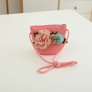 Close-up of a pink woven straw shoulder bag for girls with 3D floral fabric decorations