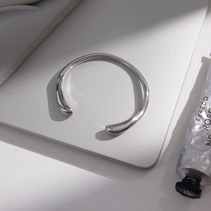 Bracelet jonc argenté poli aux extrémités en gouttes sur une surface d'ordinateur