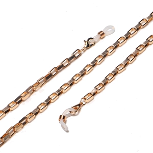Detail of golden metal eyewear chain featuring rectangular links with textured engravings