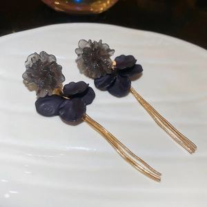 Detail of floral earrings with dark acrylic petals and long golden metal tassels