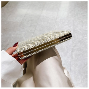 Detail of beige woven evening clutch bag with elegant gold metal frame and chain