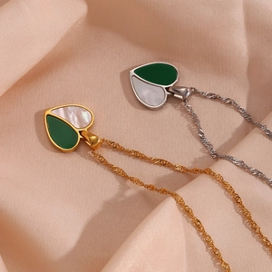 Detail of heart-shaped shell and green enamel pendant on a gold and silver wave chain