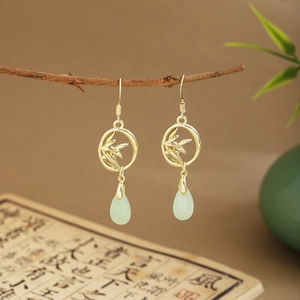 Detail of golden bamboo leaf ring earrings with pale green teardrop jade pendants