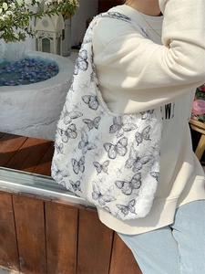 Chic butterfly print canvas shoulder bag with textured tweed finish and fringe details