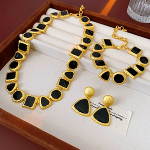 Detail view of vintage geometric jewelry set with matte gold base and black enamel inlay