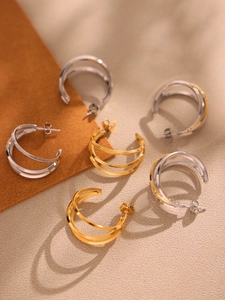 Detail of triple-layer U-shaped earrings in polished gold, silver and mixed tones