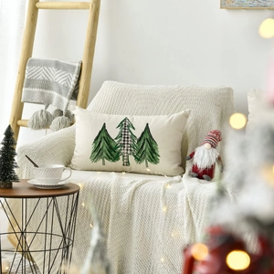 Close-up of linen Christmas pillowcase with printed trees on a cozy knit chair