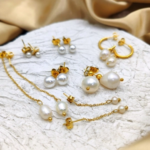 Detailed collection of gold plated pearl earrings on champagne silk and stone backdrop