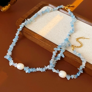 Detailed macro view of aquamarine stones and pearls on a premium necklace displayed on wood