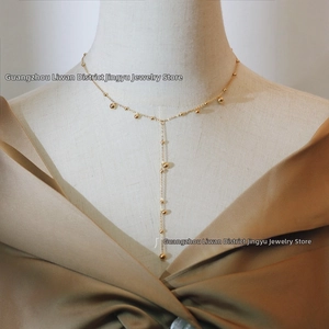Detail of elegant 18K gold plated Y-shaped tassel necklace with polished golden beads