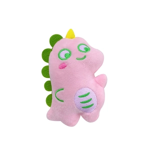 Pink cartoon dinosaur plush keychain with green spikes and yellow horns on white background