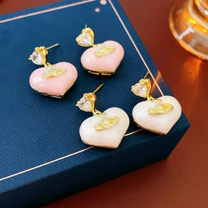 Macro shot of gold-plated heart earrings in pink and white enamel with crystal accents