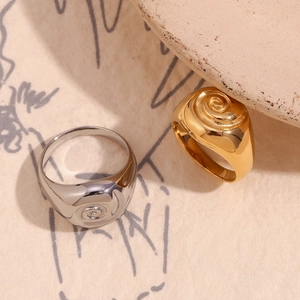 Close-up of vintage gold and silver swirl textured signet rings on a stone surface