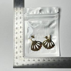 Detailed size measurement of golden shell-shaped earrings with L-shaped ruler scale