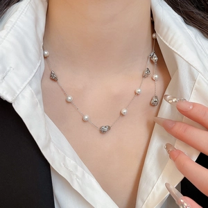 Detailed close-up of a French vintage pearl necklace with a silver heart-shaped pendant