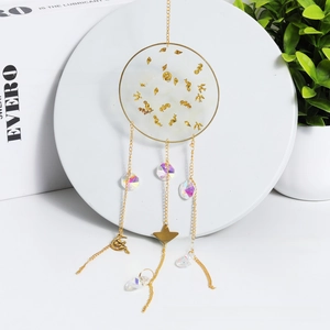 Detail of crystal suncatcher with golden moon and star pendants on white stand