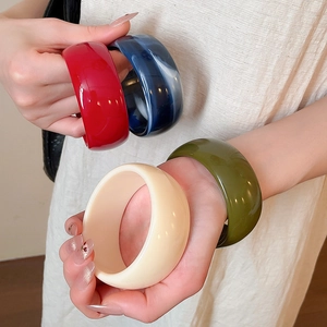 Detail of wide acrylic bangles in red blue marble olive green and cream colors