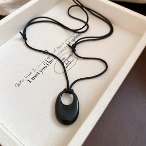 Détail d'un pendentif ovale noir sur cordon dans un écrin à bijoux haut de gamme