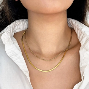 Close-up of a double-layered gold twist and snake chain necklace worn by a model