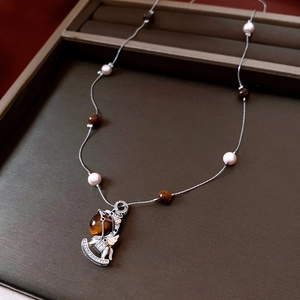 Detailed shot of tiger eye stone rocking horse pendant with pearls on a silver chain