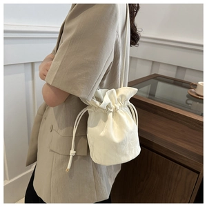 Minimalist white drawstring bucket bag with pleated texture and slim shoulder strap
