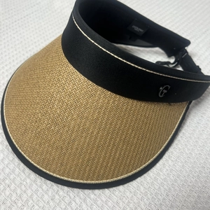Detail of straw sun visor featuring woven texture and black headband with metal G logo