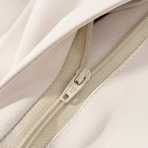 Detailopname van de onzichtbare rits op de beige hoogwaardige stof van de dames set
