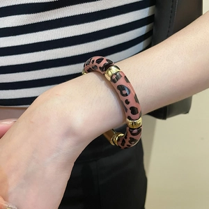 Vue détaillée du bracelet en acrylique à motif léopard avec perles intercalaires dorées