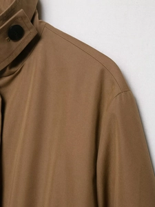 Close-up of the textured brown twill fabric and button detail on the trench coat shoulder