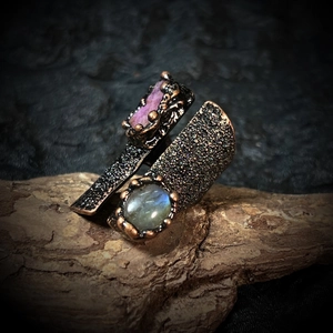 Macro detail of handmade vintage wide ring with labradorite and raw pink gemstone